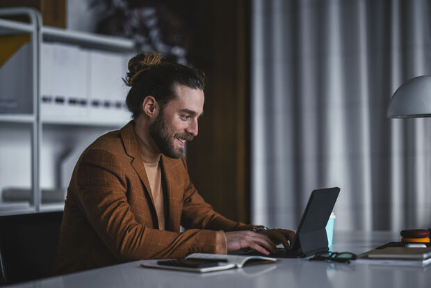 Mann sitzt entspannt mit Tablet und prüft digitale Dokumente – sinnbildlich für ortsunabhängigen Zugriff auf Geschäftspost über einen digitalen Posteingang.