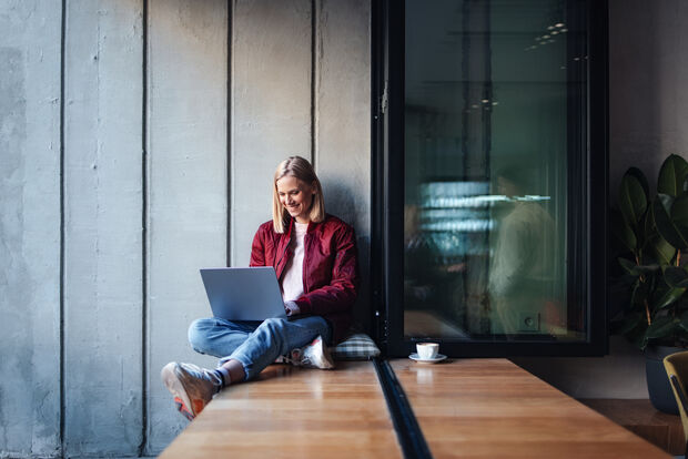 A woman is sitting with her laptop in a modern co-working space, working at a flexible workstation.