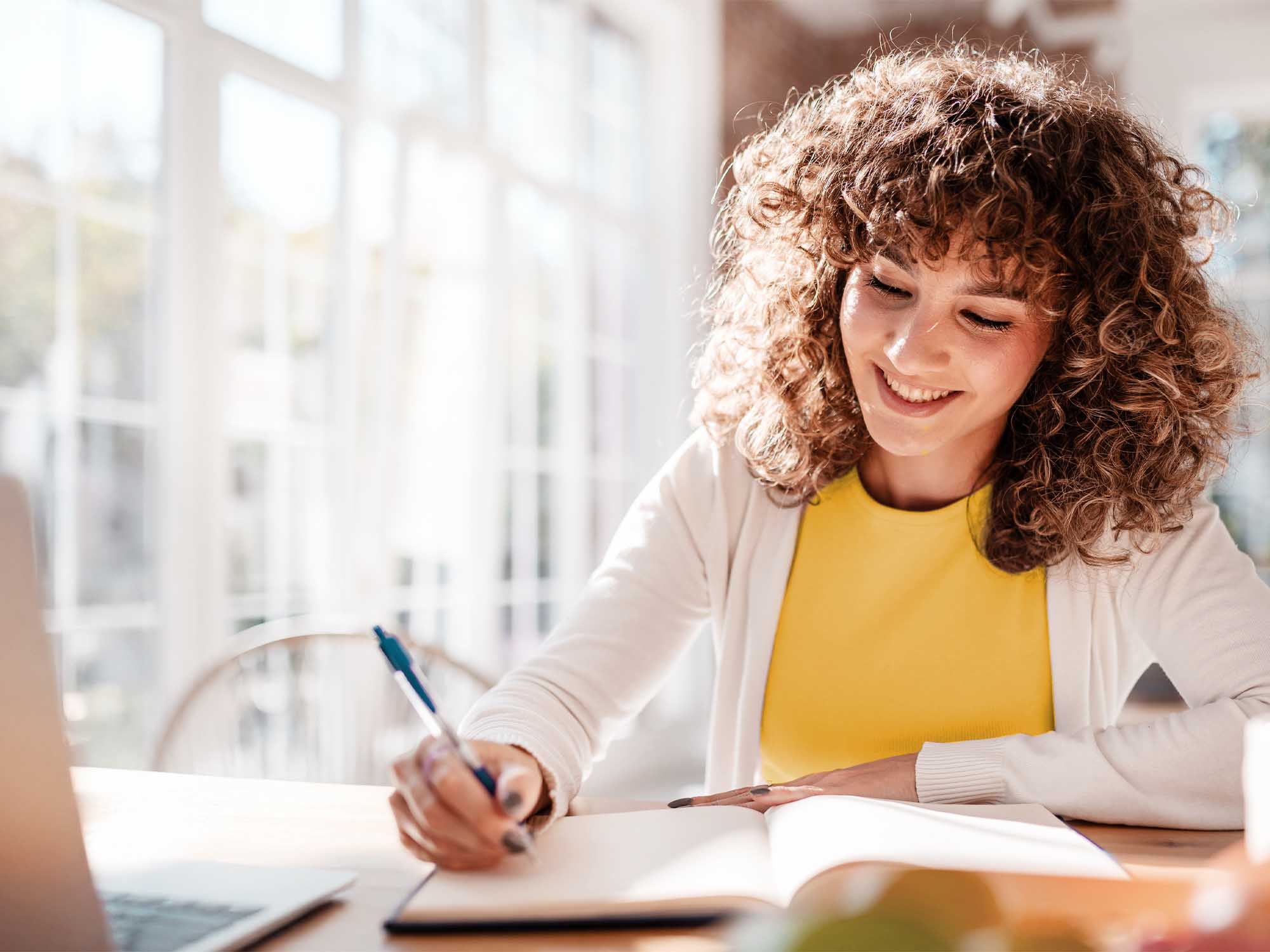 cheerful woman at the table with notebook and laptop